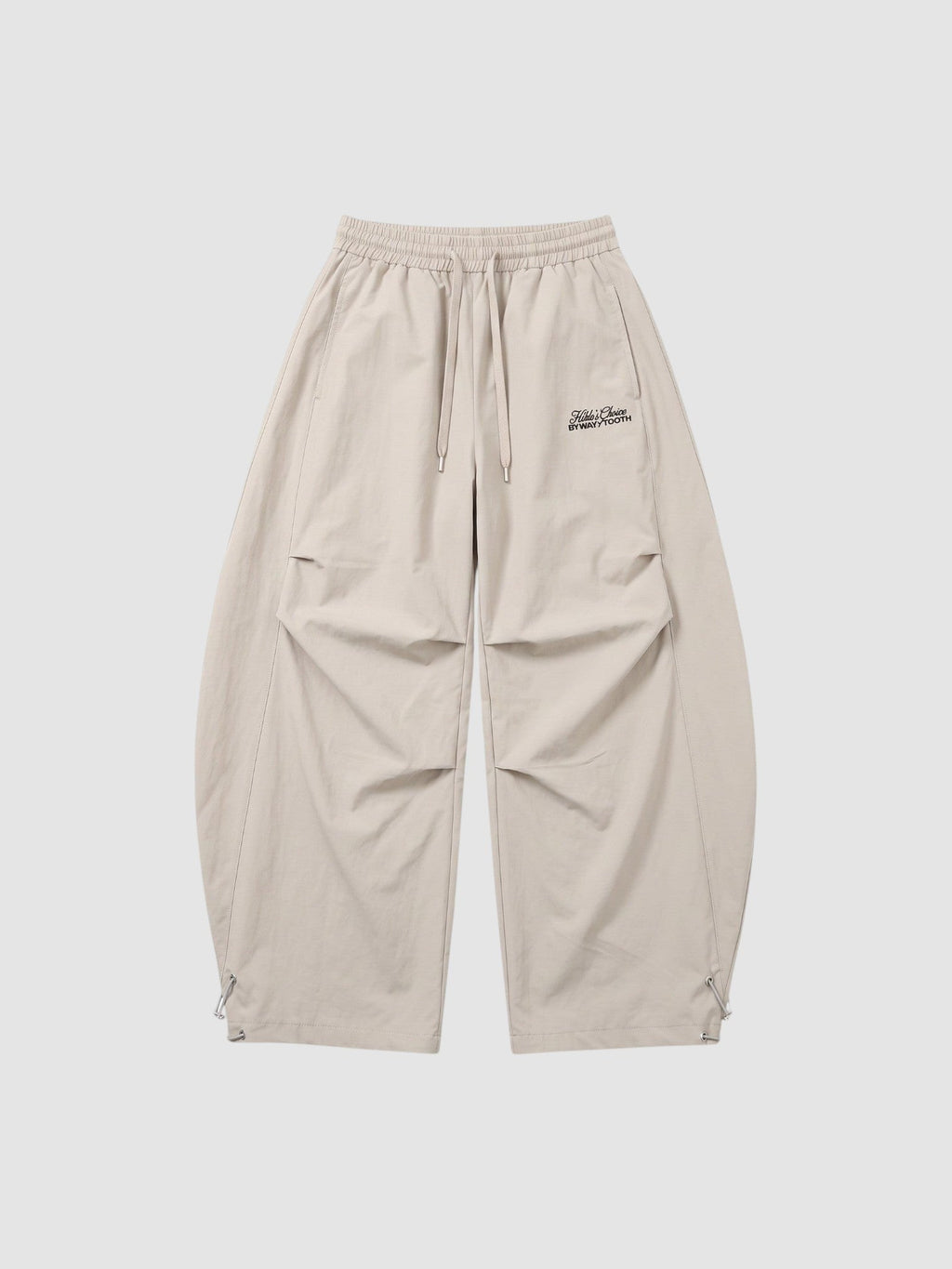 Y2K Avenue beige oversized nylon joggers with elastic waist, side pockets, and white embroidered script logo on thigh.