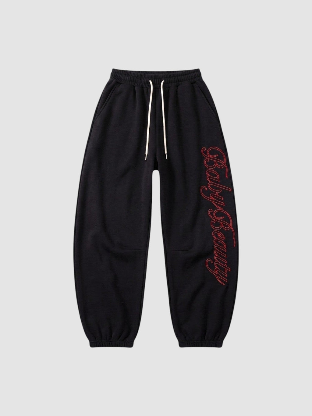 Y2K Avenue black oversize joggers with red calligraphy lettering down the leg and a cream drawstring waist.