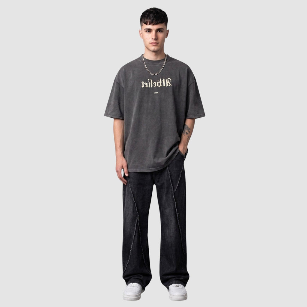 Y2K Avenue black Y2K jeans with diagonal raw-edge seams worn by a model with a grey graphic t-shirt and sneakers