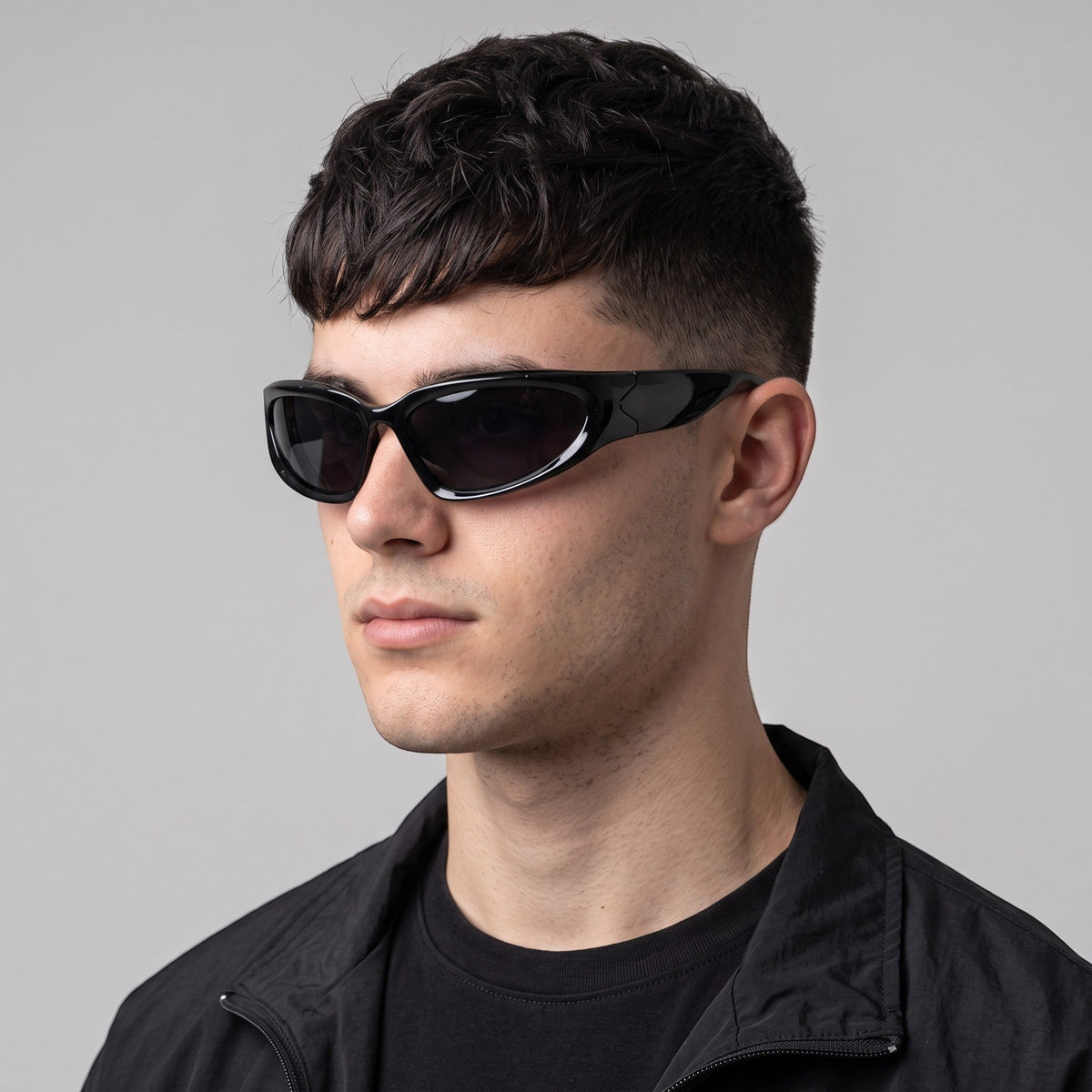 Y2K AVENUE black wraparound gorpcore sunglasses with dark tinted lenses worn by a man in a techwear style