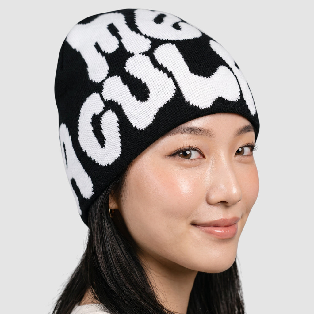 Y2K AVENUE black skullie beanie with white graffiti bubble lettering worn by a model