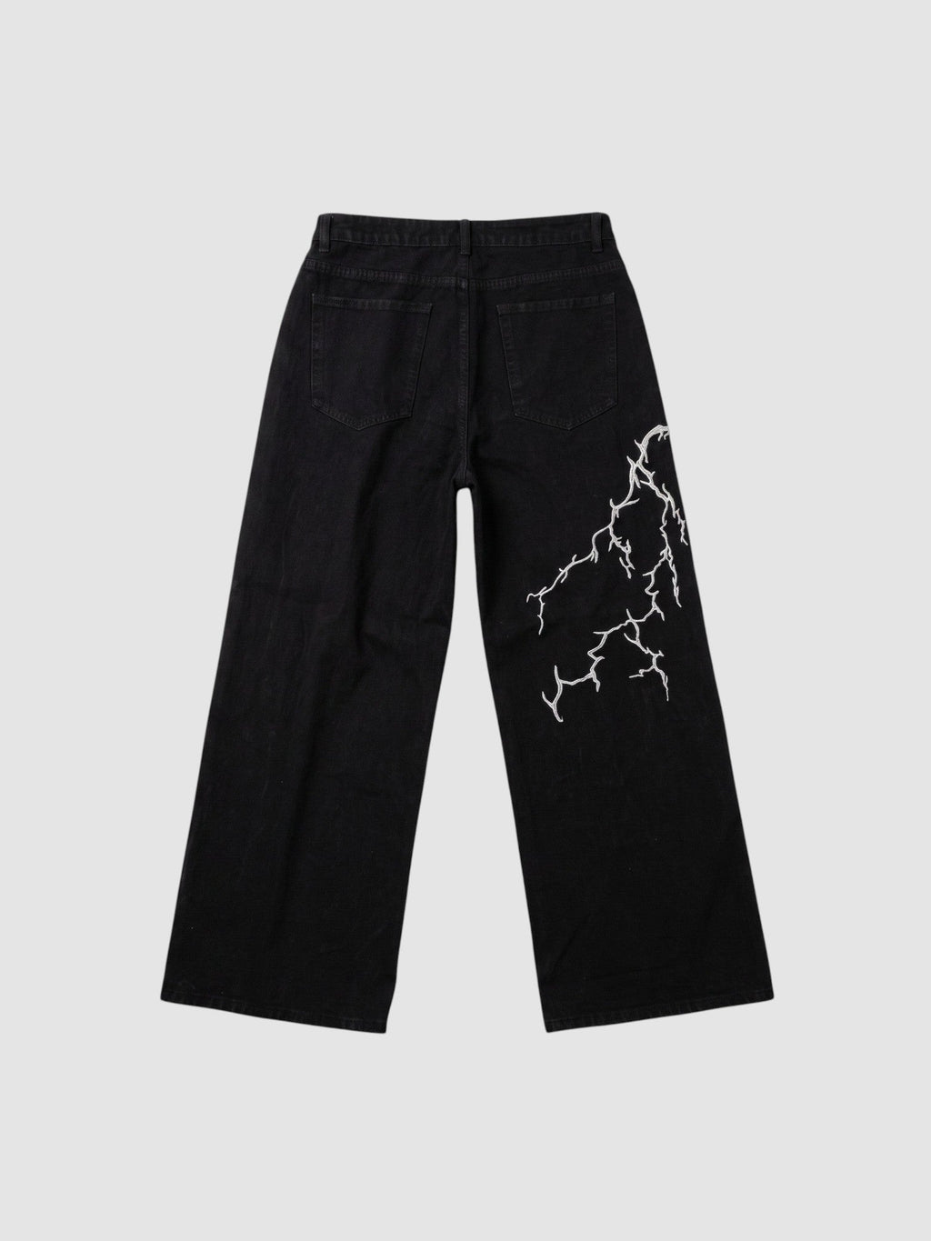Y2K Avenue black wide-leg denim jeans featuring an asymmetrical white lightning bolt embroidery on the back leg.