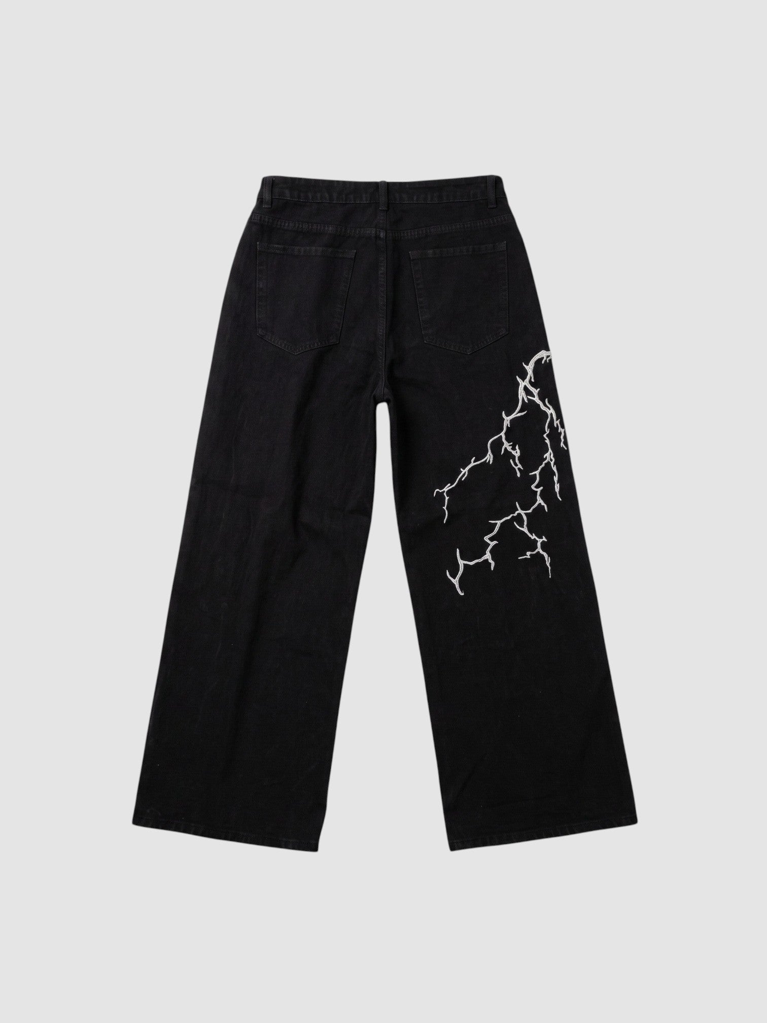 Y2K Avenue black wide-leg denim jeans featuring an asymmetrical white lightning bolt embroidery on the back leg.