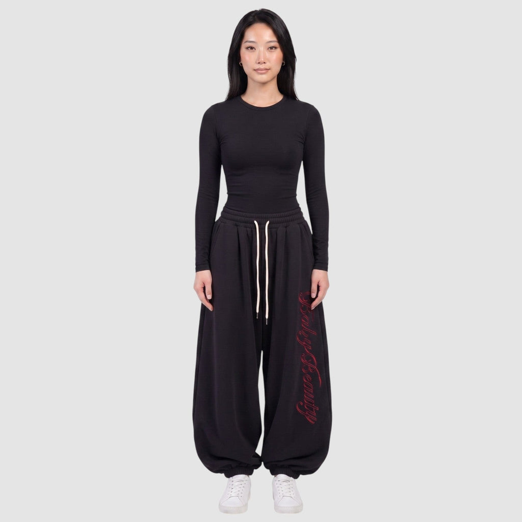 Y2K Avenue black oversize joggers featuring red vertical calligraphy lettering on the leg and a cream drawstring.