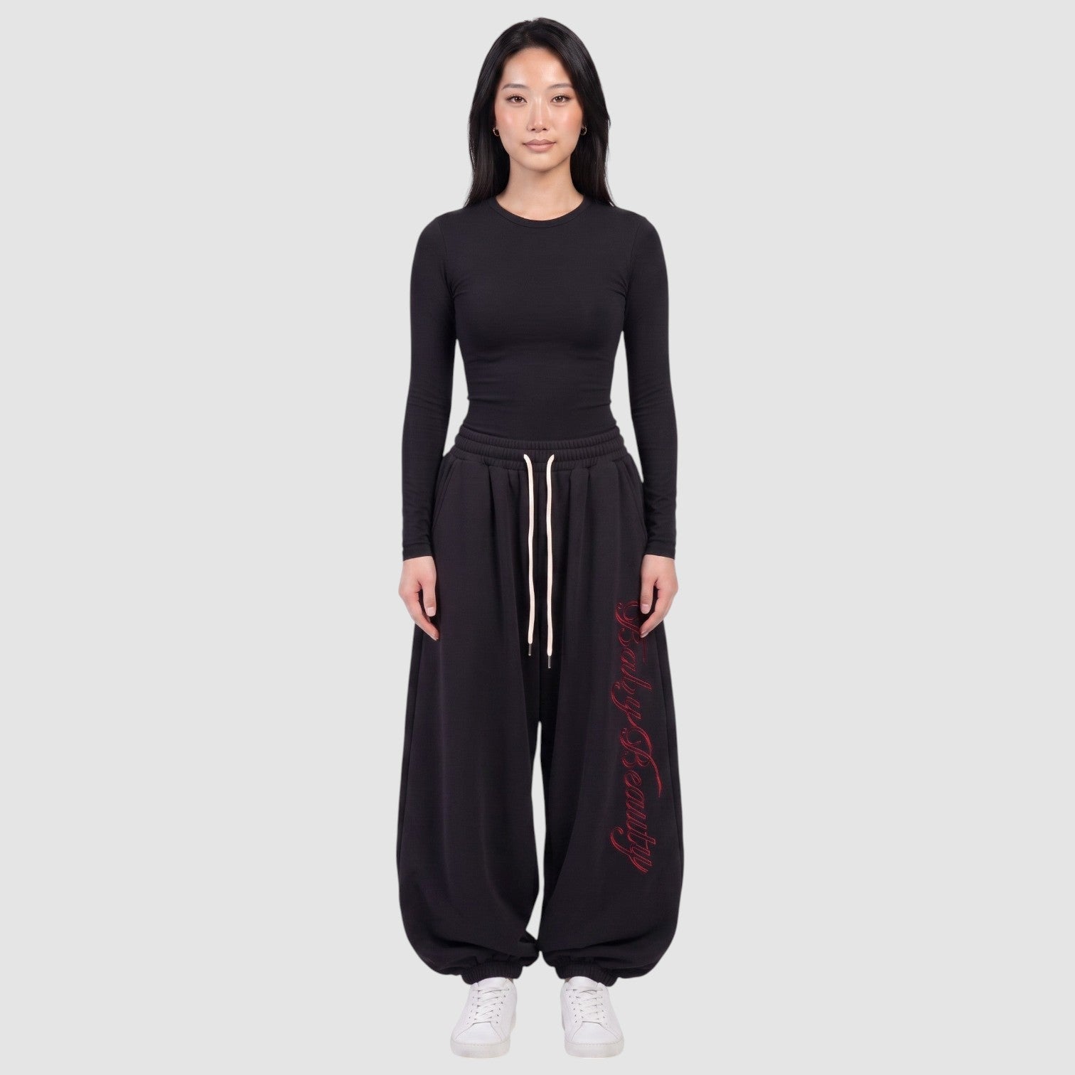 Y2K Avenue black oversize joggers featuring red vertical calligraphy lettering on the leg and a cream drawstring.