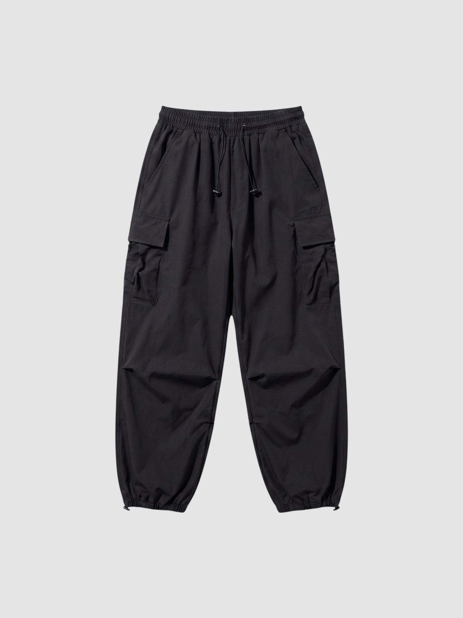 Y2K Avenue black parachute cargo pants with a loose fit, elastic drawstring waist, and side flap pockets.