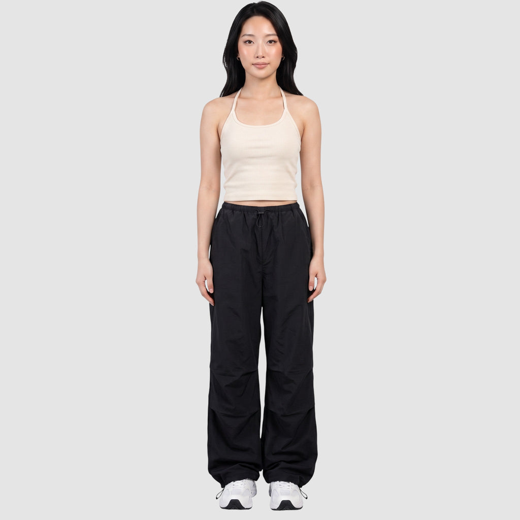 Model wearing Y2K AVENUE black parachute pants with a high elastic waist, side pockets, and adjustable ankle cords.