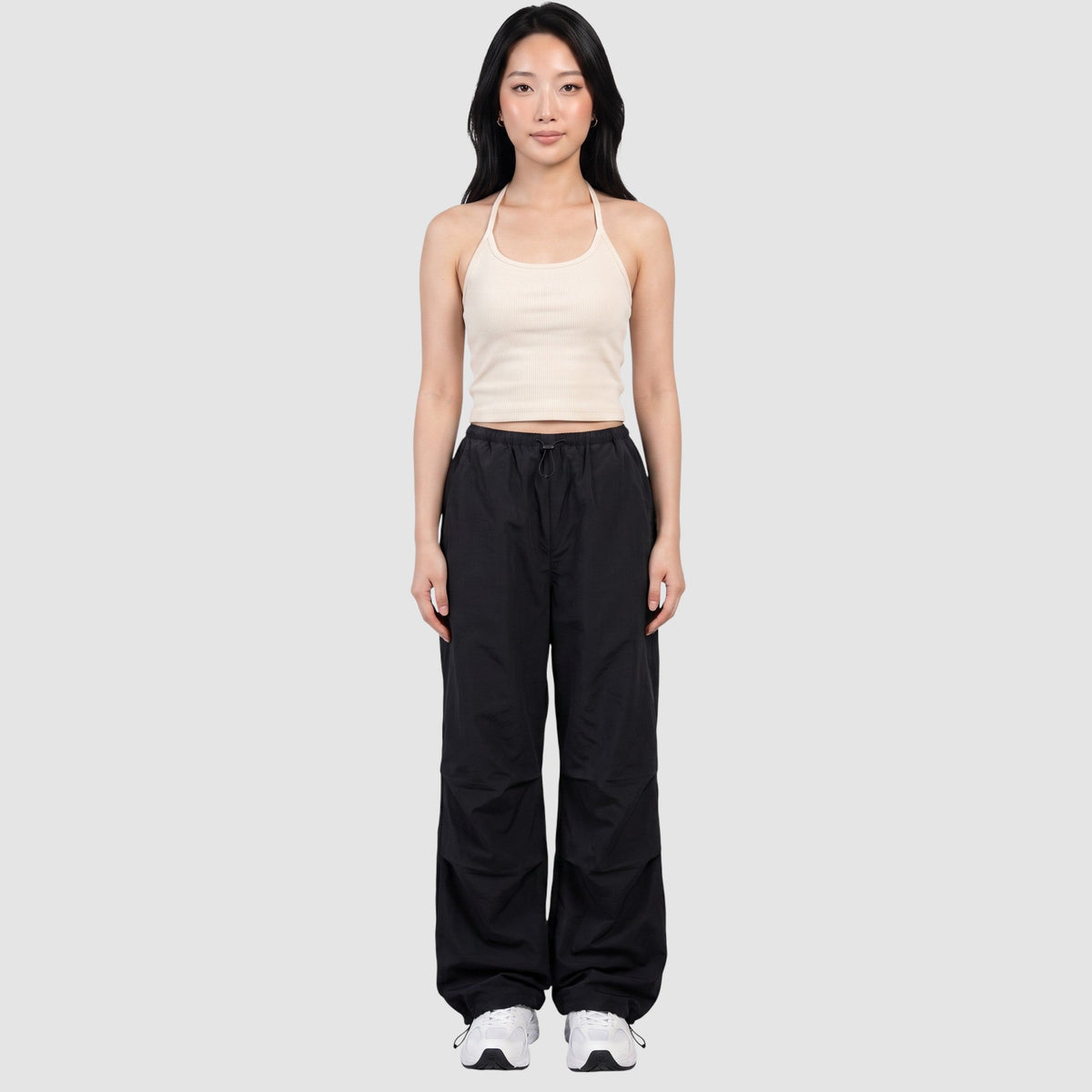 Model wearing Y2K AVENUE black parachute pants with a high elastic waist, side pockets, and adjustable ankle cords.