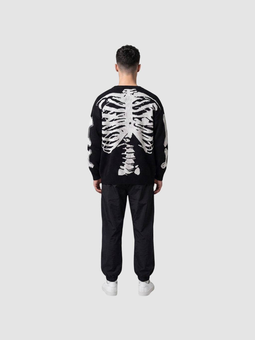 Y2K AVENUE black knit sweater with white 3D skeleton ribcage and spine design on the back, worn by a man.