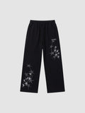 Y2K Avenue black wide leg sweatpants featuring grey four-pointed star prints and an elastic drawstring waistband.