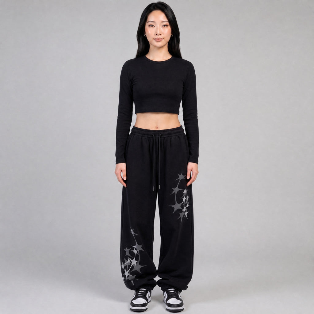Y2K AVENUE black wide leg joggers with grey star prints, elastic waist, and white drawstring on a female model