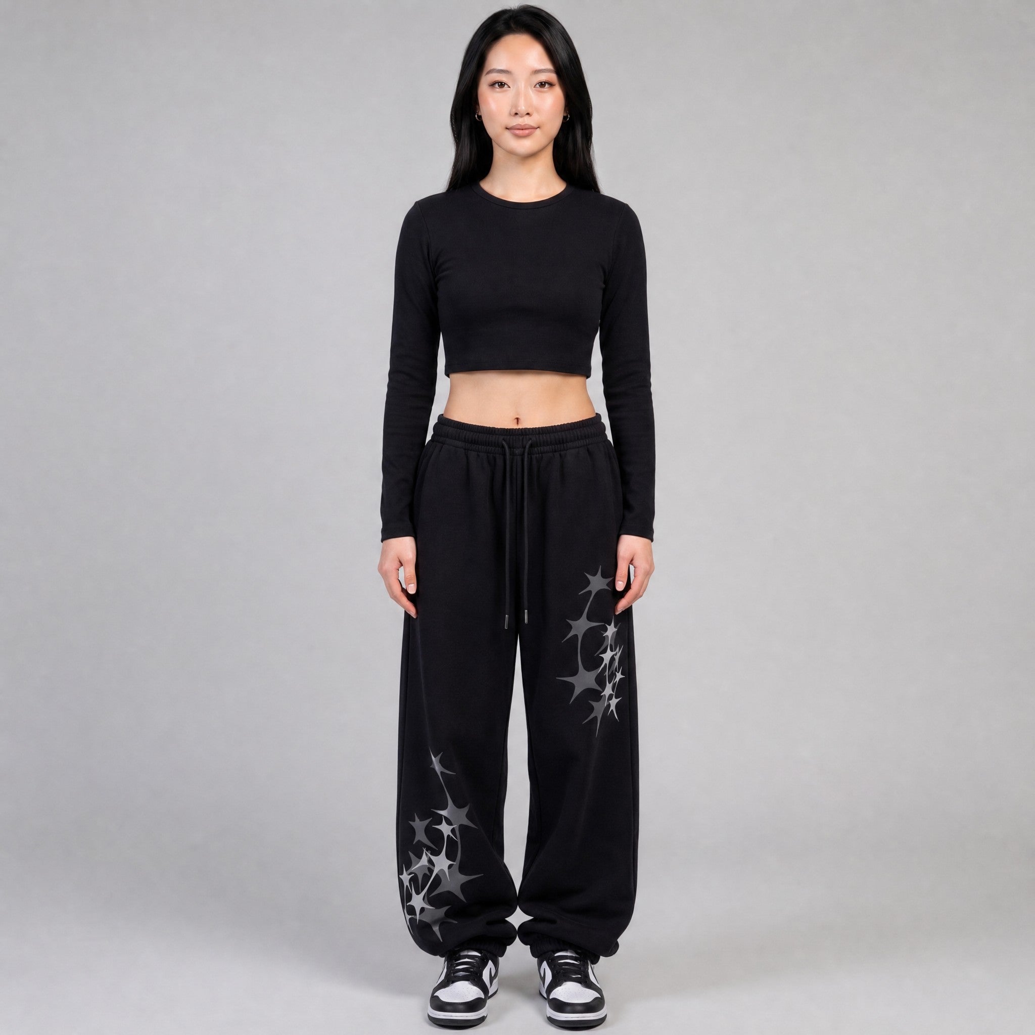 Y2K AVENUE black wide leg joggers with grey star prints, elastic waist, and white drawstring on a female model