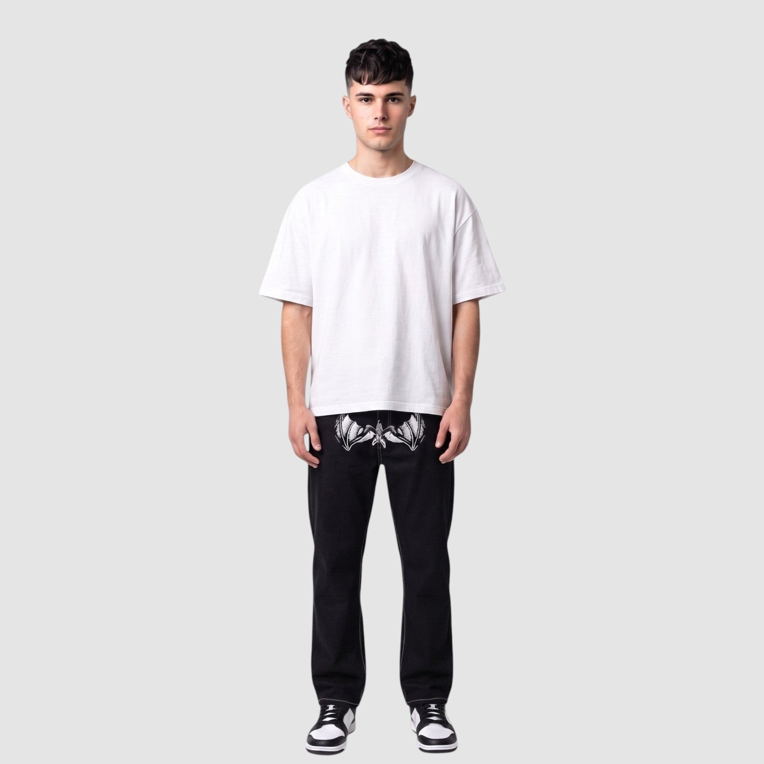 Y2K Avenue black straight-leg denim jeans with white wing print on thighs and contrast stitching on a male model