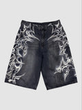 Y2K Avenue black denim jorts featuring white airbrushed tribal motifs and a loose, knee-length fit with raw hems.