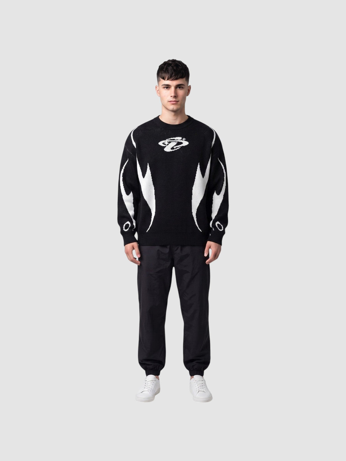 Y2K AVENUE black and white knit sweater with flame motifs and chest logo worn by a male model with black trousers