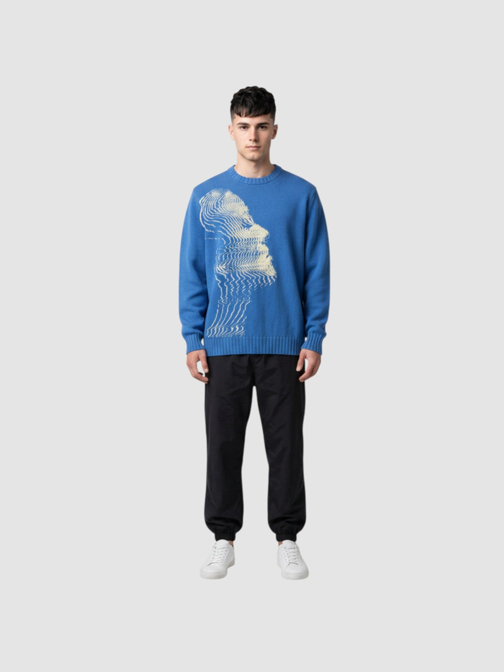 Model wearing Y2K AVENUE blue oversized knit sweater with cream wavy face graphic, paired with black cargo pants