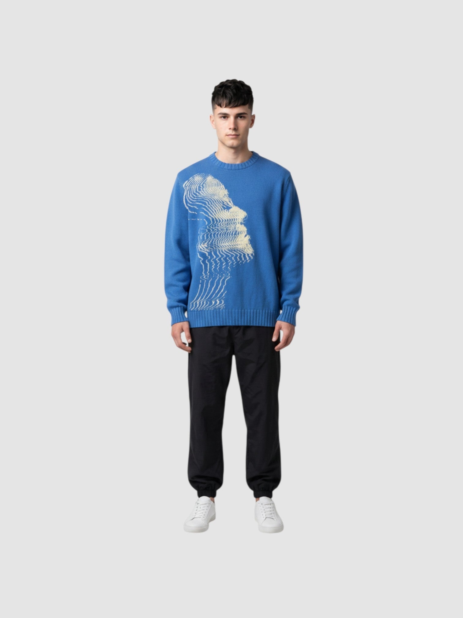 Model wearing Y2K AVENUE blue oversized knit sweater with cream wavy face graphic, paired with black cargo pants