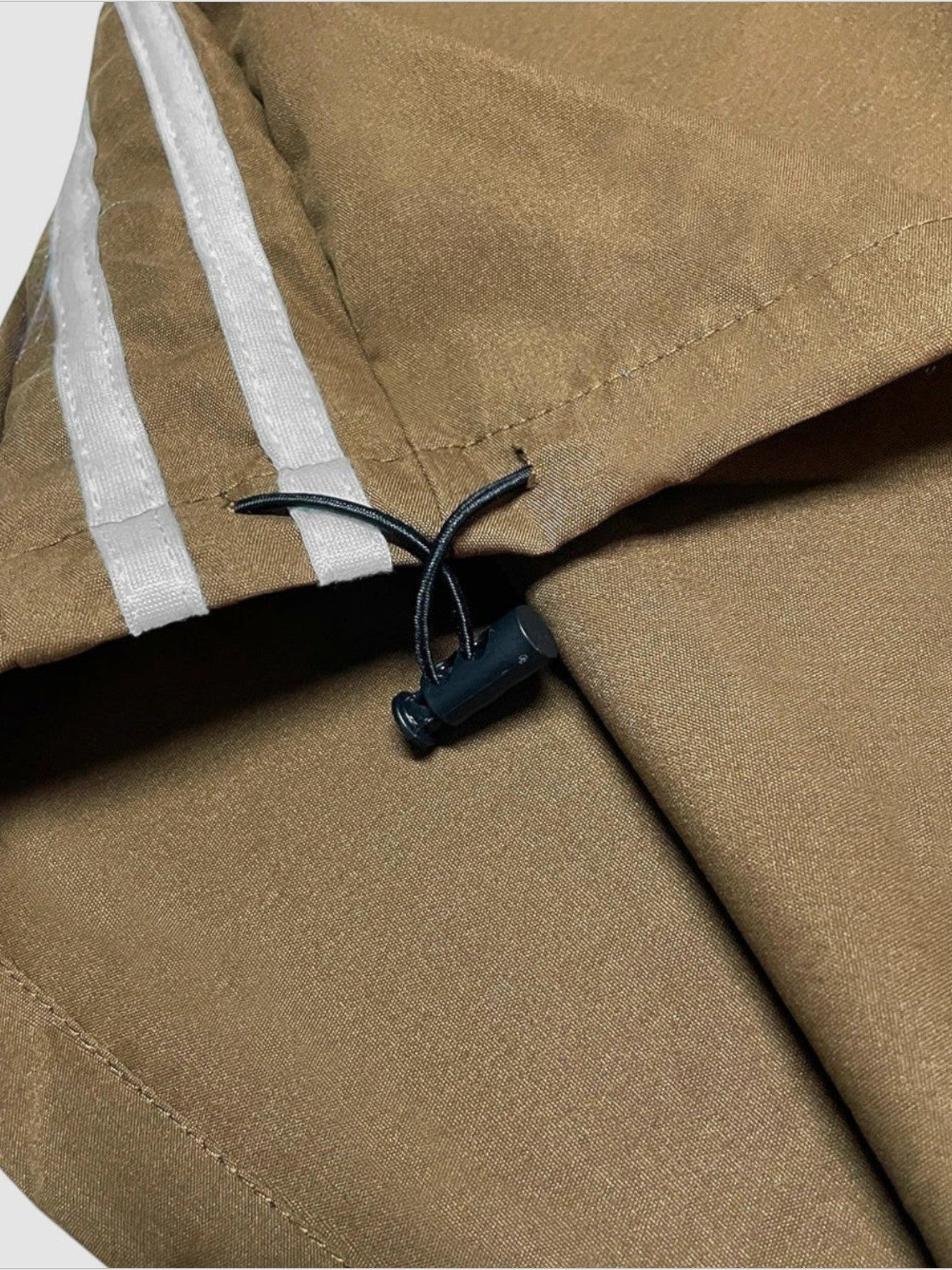 Y2K AVENUE deep brown nylon oversized joggers featuring white side stripes and an adjustable drawstring hem detail.