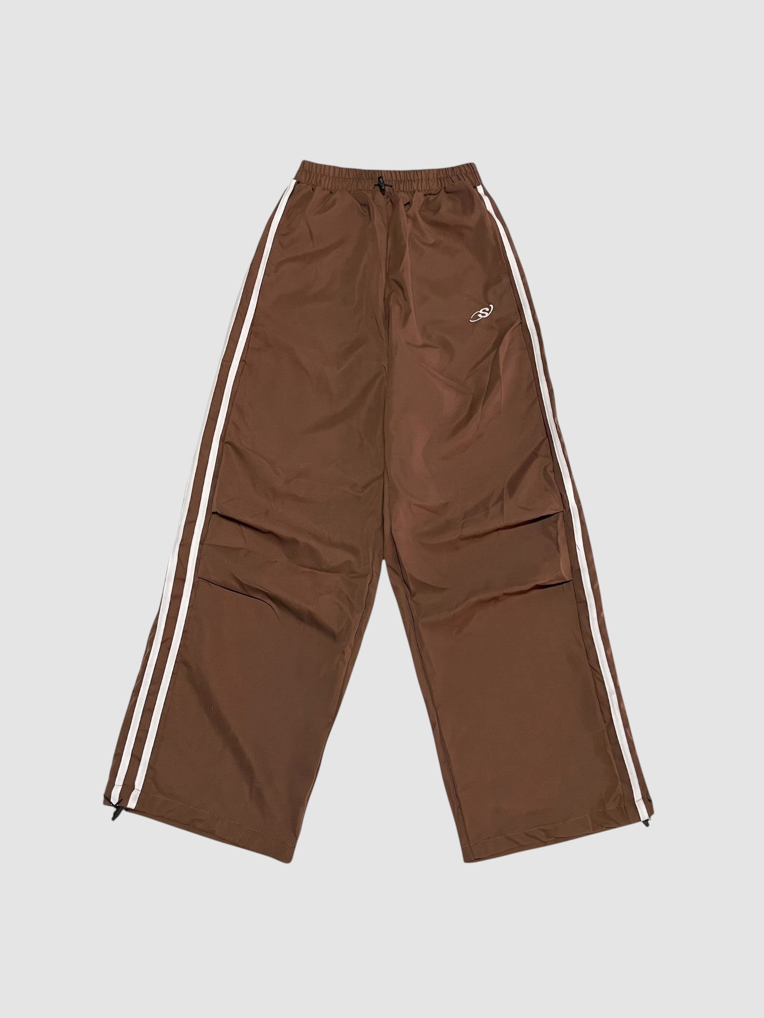 Y2K Avenue brown oversized nylon joggers with white side stripes and an elastic high waist with drawstring.