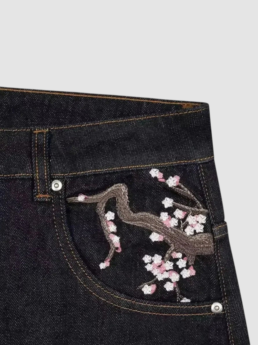 Y2K Avenue dark denim jeans featuring detailed cherry blossom embroidery on the back pocket in pink and white thread.