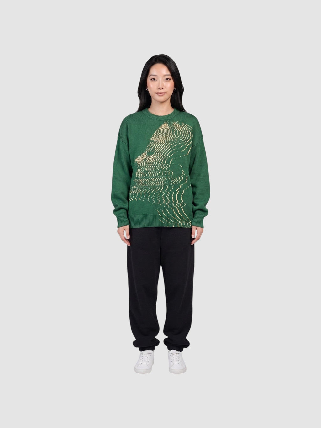 Model wearing a Y2K AVENUE forest green oversized acrylic knit sweater featuring a cream wavy face graphic pattern.