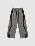 Y2K AVENUE grey and black panelled Y2K trousers with white piping, decorative zippers, and adjustable ankle cords.