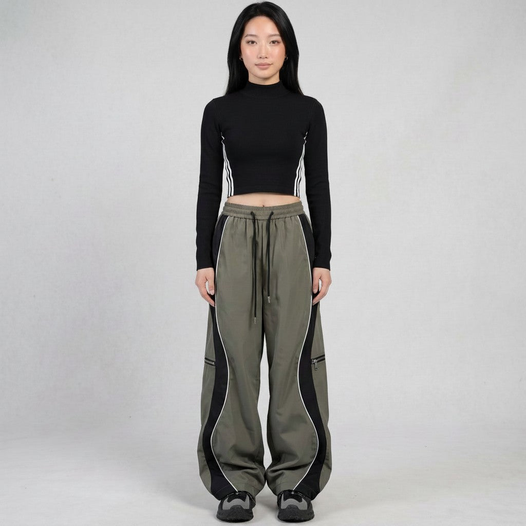 Y2K AVENUE two-tone grey panelled trousers with white piping, decorative zippers, and adjustable ankle drawstrings.
