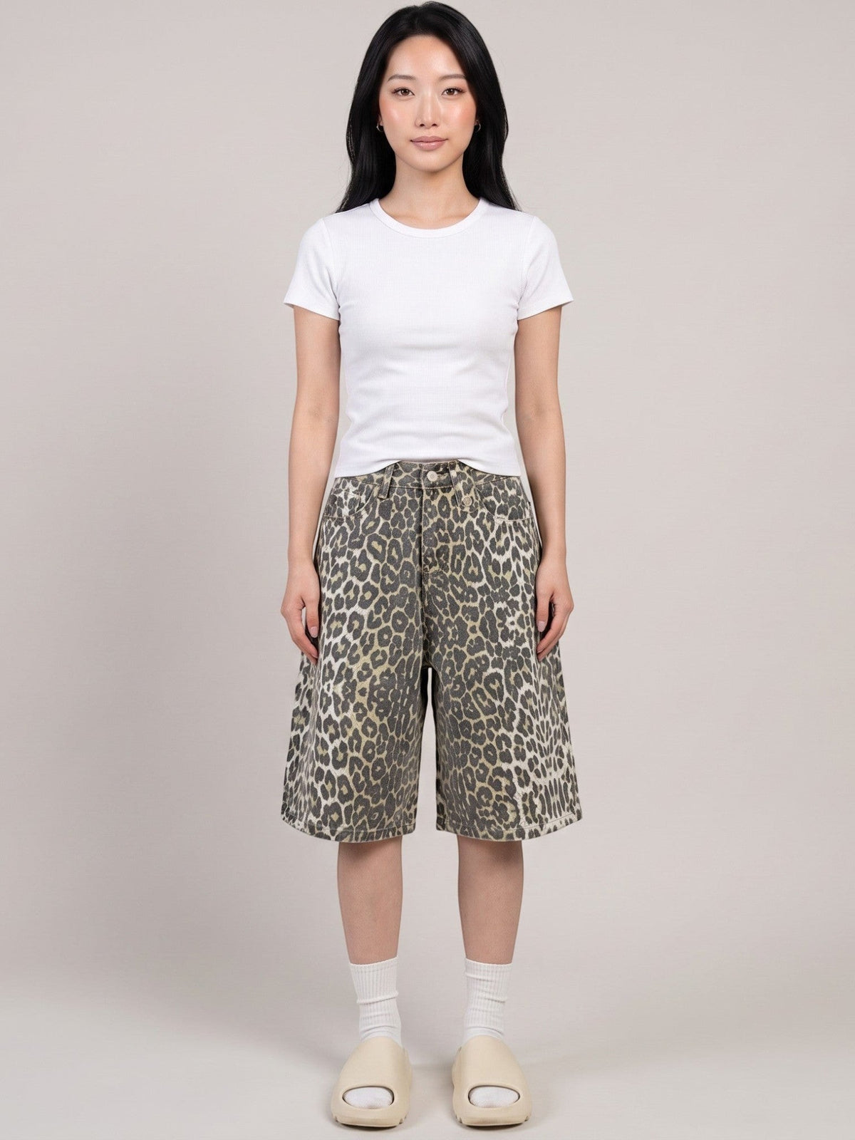 Model wearing Y2K Avenue high-waisted khaki leopard print denim bermuda shorts with a white t-shirt and slides.