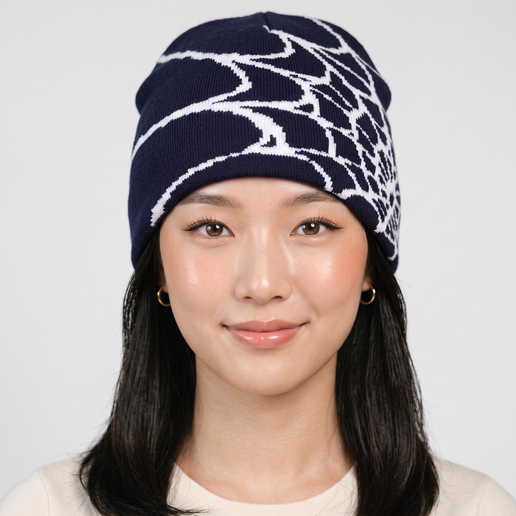 Y2K AVENUE unisex navy blue knit beanie featuring a white spider web pattern, worn by a model for winter warmth.