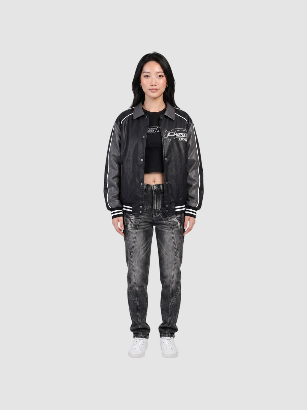 Model wearing an oversized Y2K Avenue moto jacket in charcoal grey with white piping, graphic print, and ribbed cuffs.