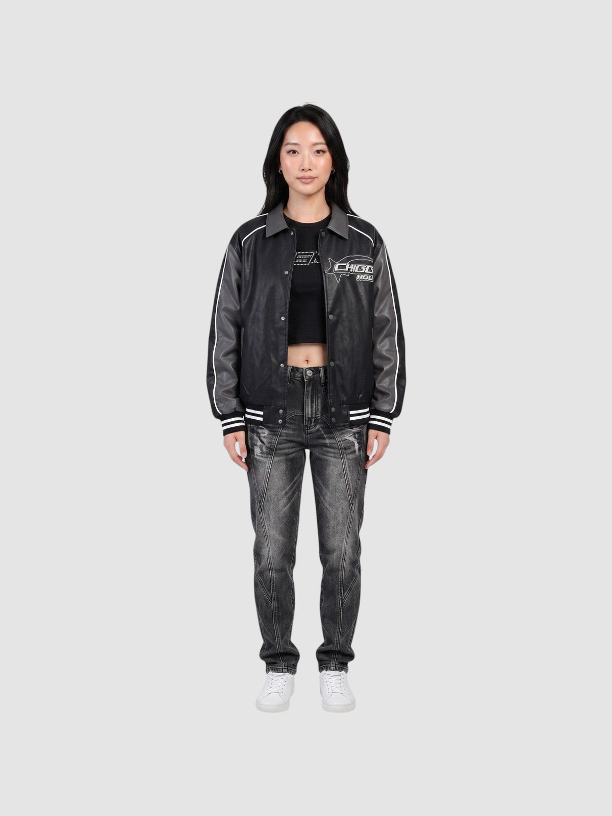 Model wearing an oversized Y2K Avenue moto jacket in charcoal grey with white piping, graphic print, and ribbed cuffs.