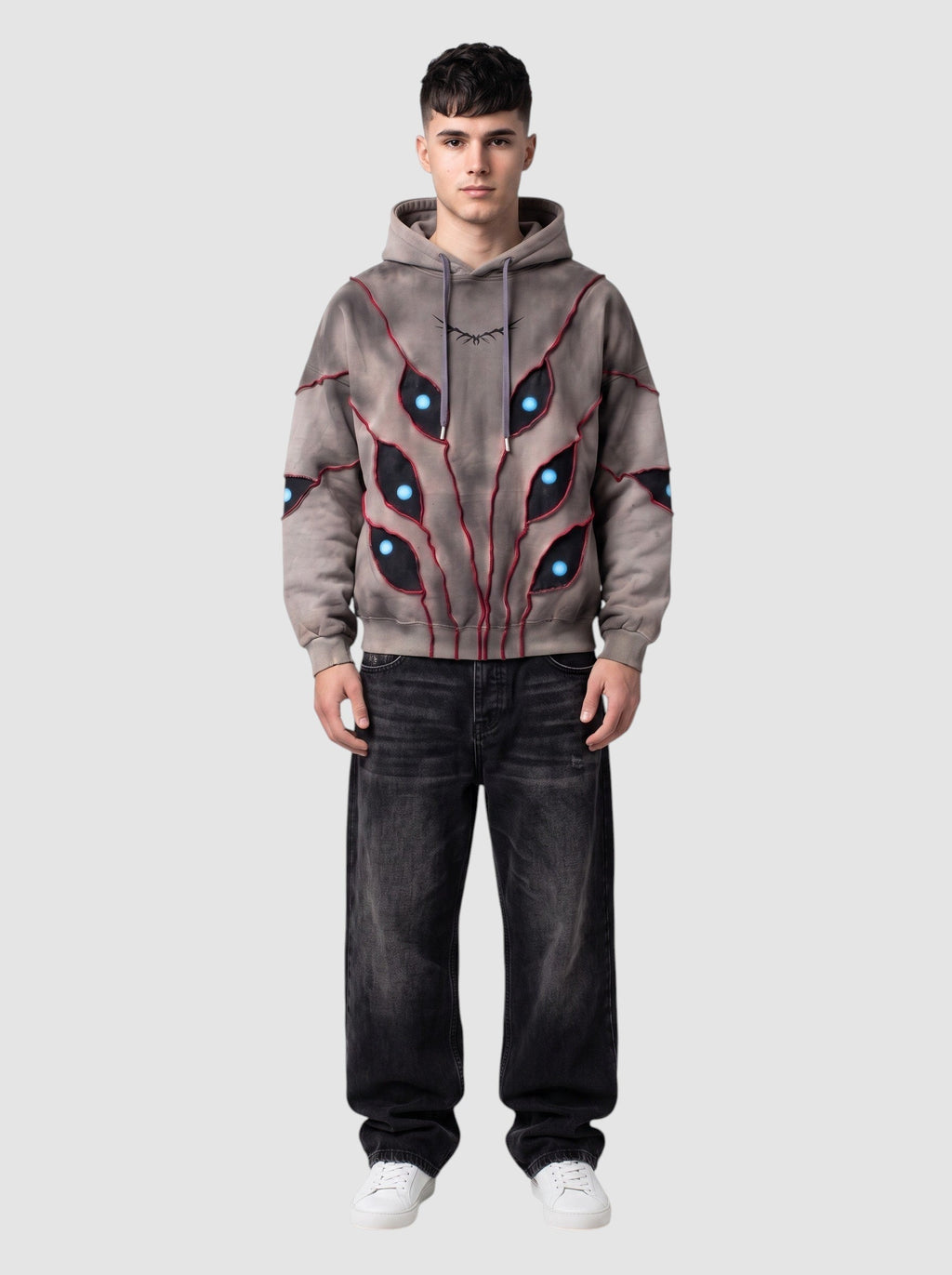 Y2K Avenue oversized beige hoodie with patchwork eye cutouts, blue pupils, and red stitching on a male model