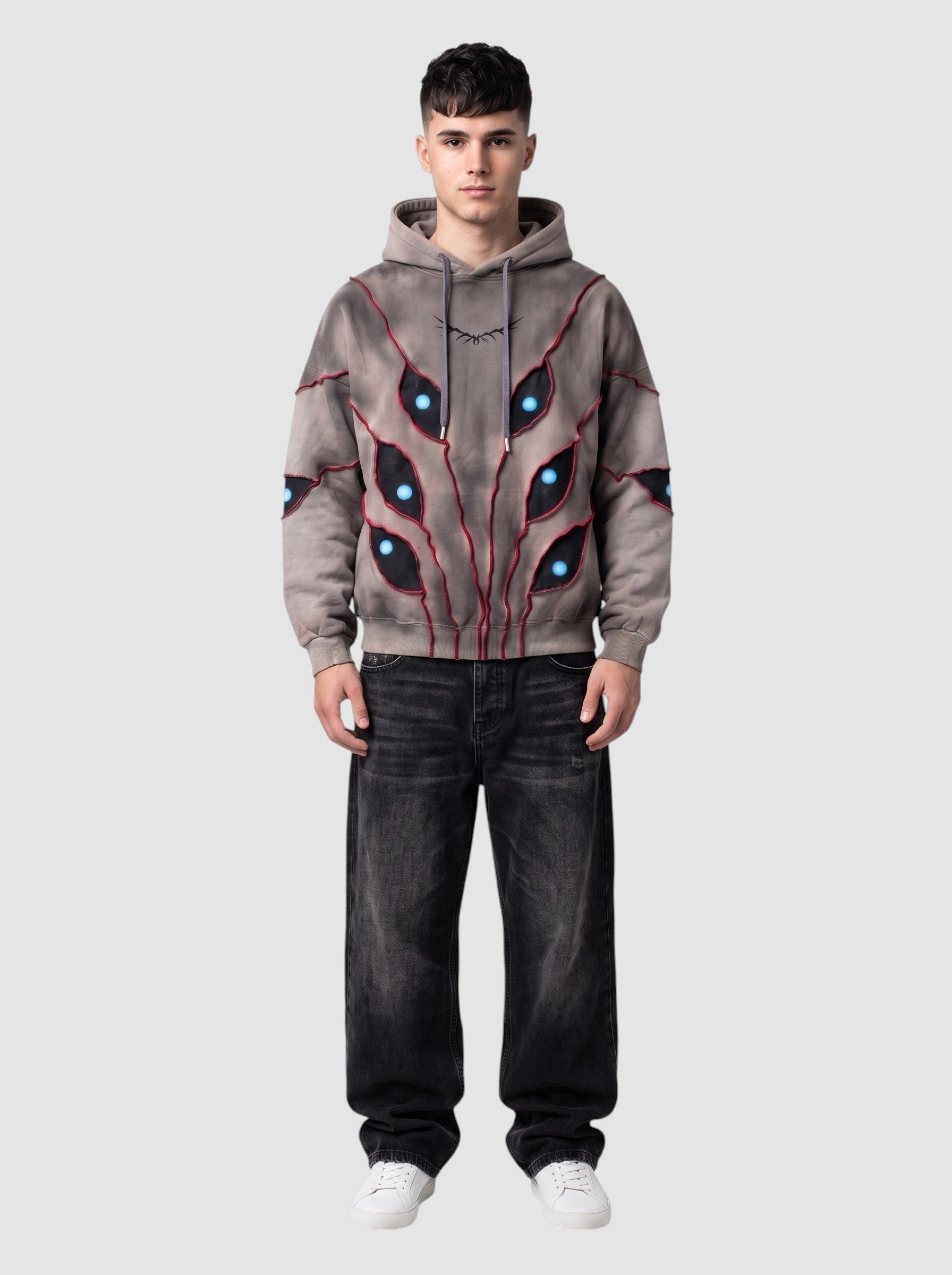 Y2K Avenue oversized beige hoodie with patchwork eye cutouts, blue pupils, and red stitching on a male model