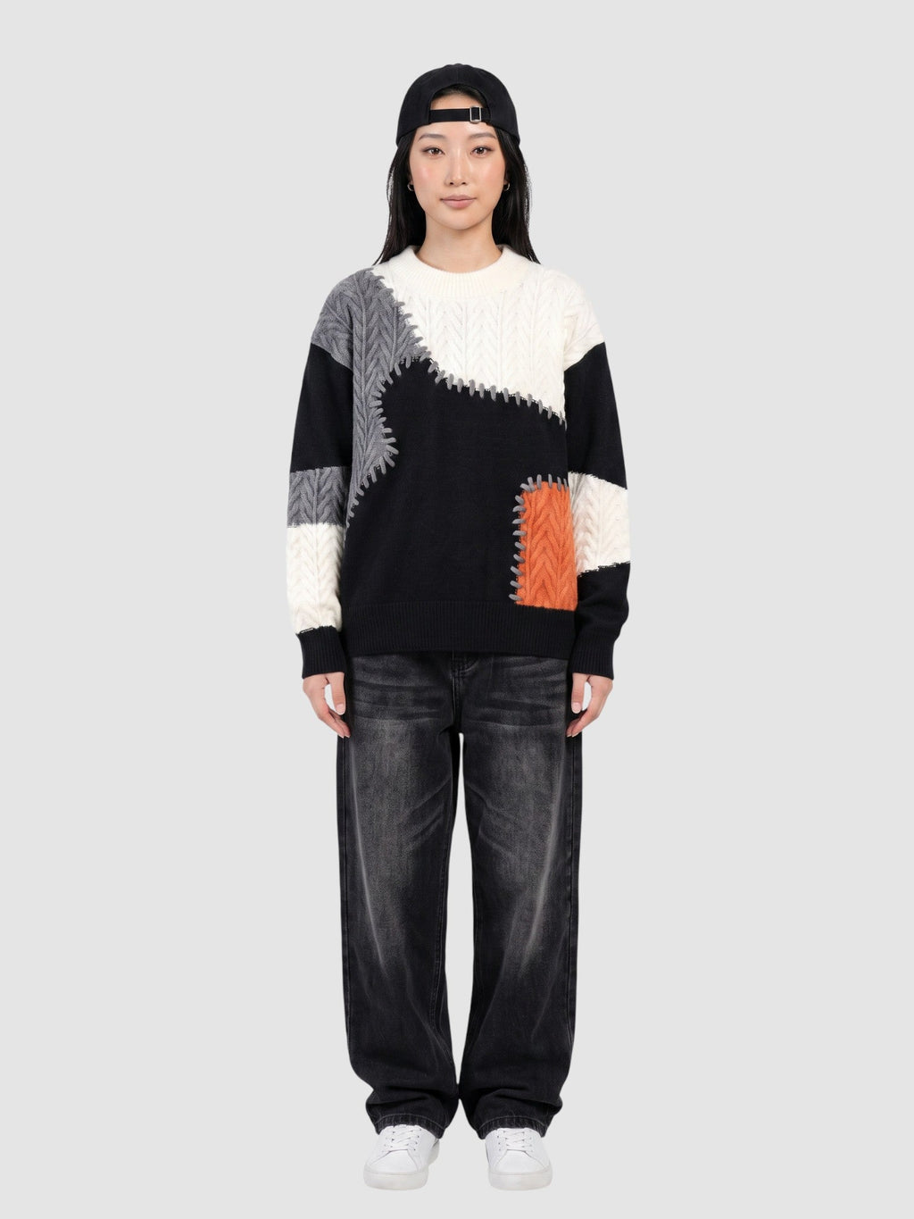 Y2K Avenue patchwork knit sweater featuring black, white, and orange panels with decorative stitching on a model