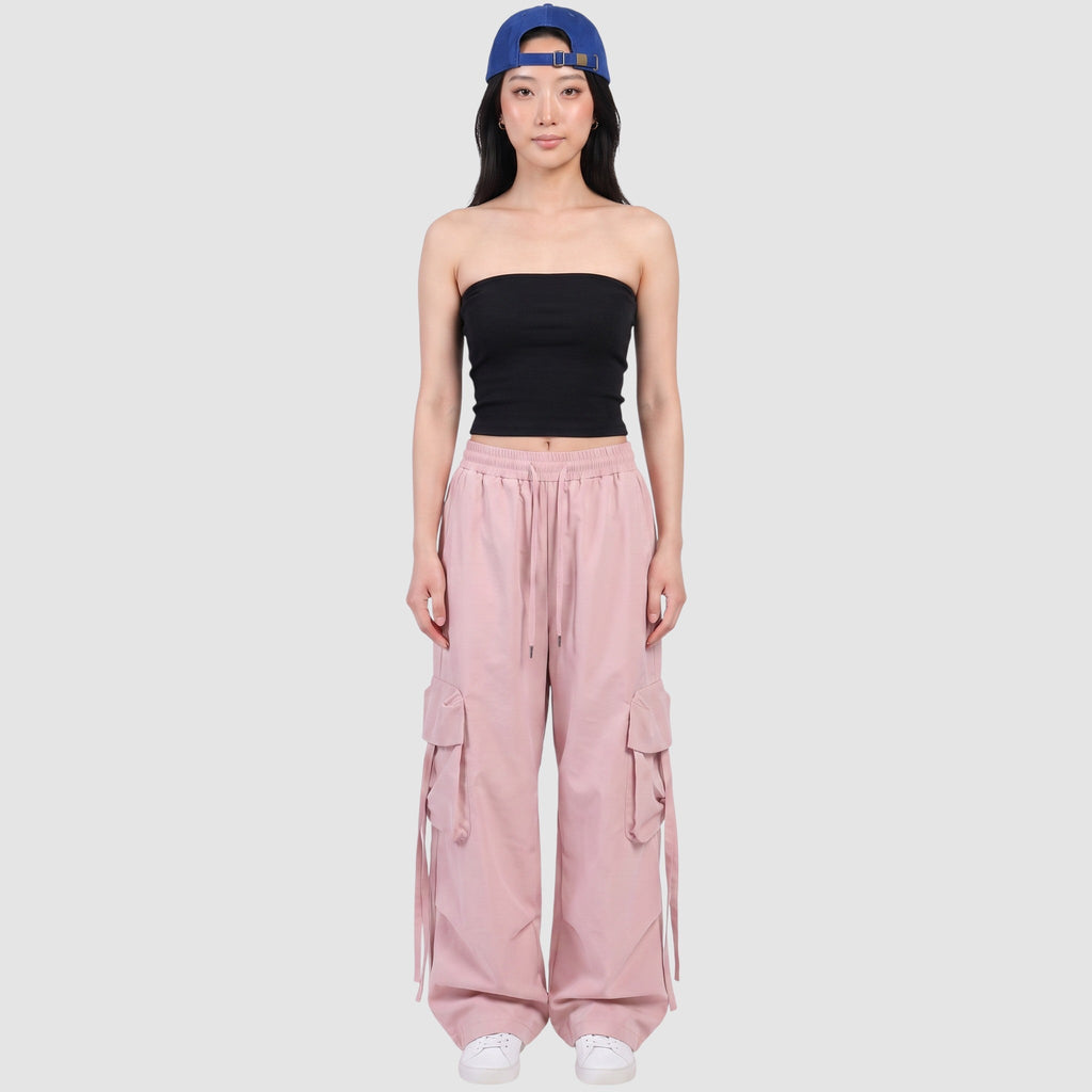 Model wearing Y2K AVENUE powder pink parachute cargo pants with side pockets, drawstring waist, and loose wide fit.