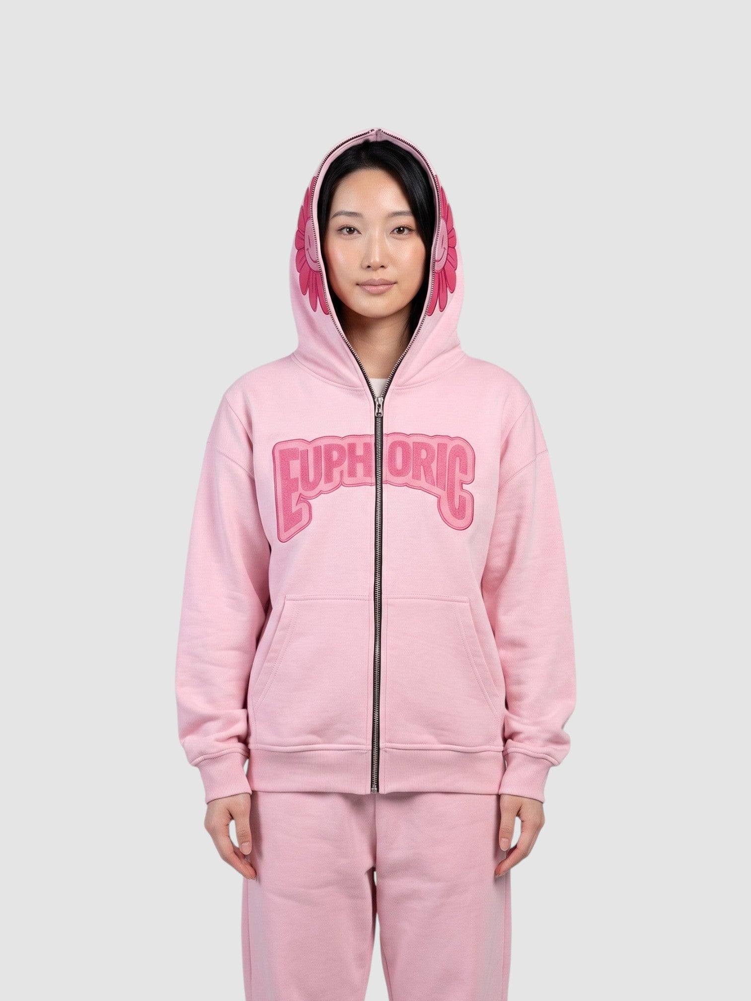 Y2K Avenue pale pink zip-up hoodie featuring a bubble letter graphic and a smiley flower detail on the hood.