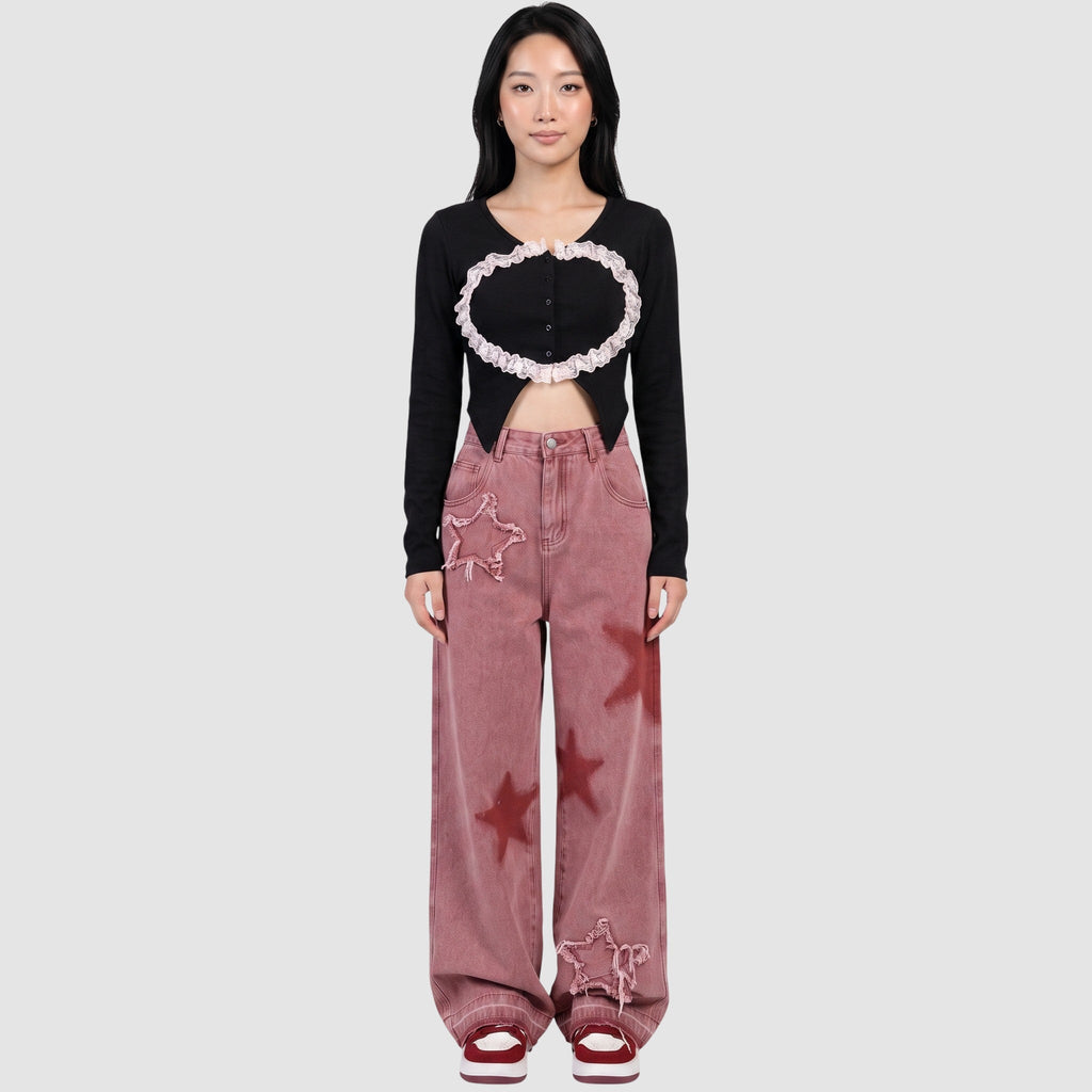 Model wearing Y2K AVENUE pink wide-leg jeans with frayed star patches and red star prints, paired with a black top.