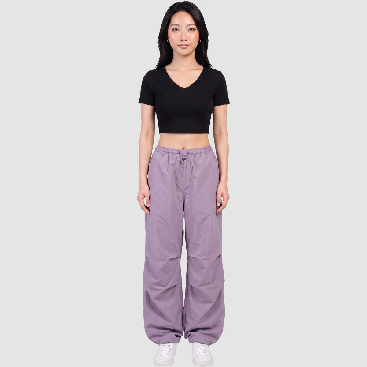 Model wearing Y2K AVENUE high-waisted purple parachute pants in matte nylon with drawstring waist and ankles.