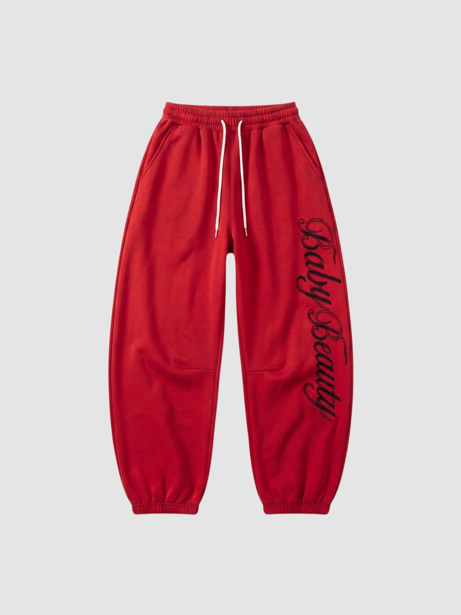 Y2K Avenue red oversized joggers featuring black calligraphy lettering down the leg and a cream drawstring waist.