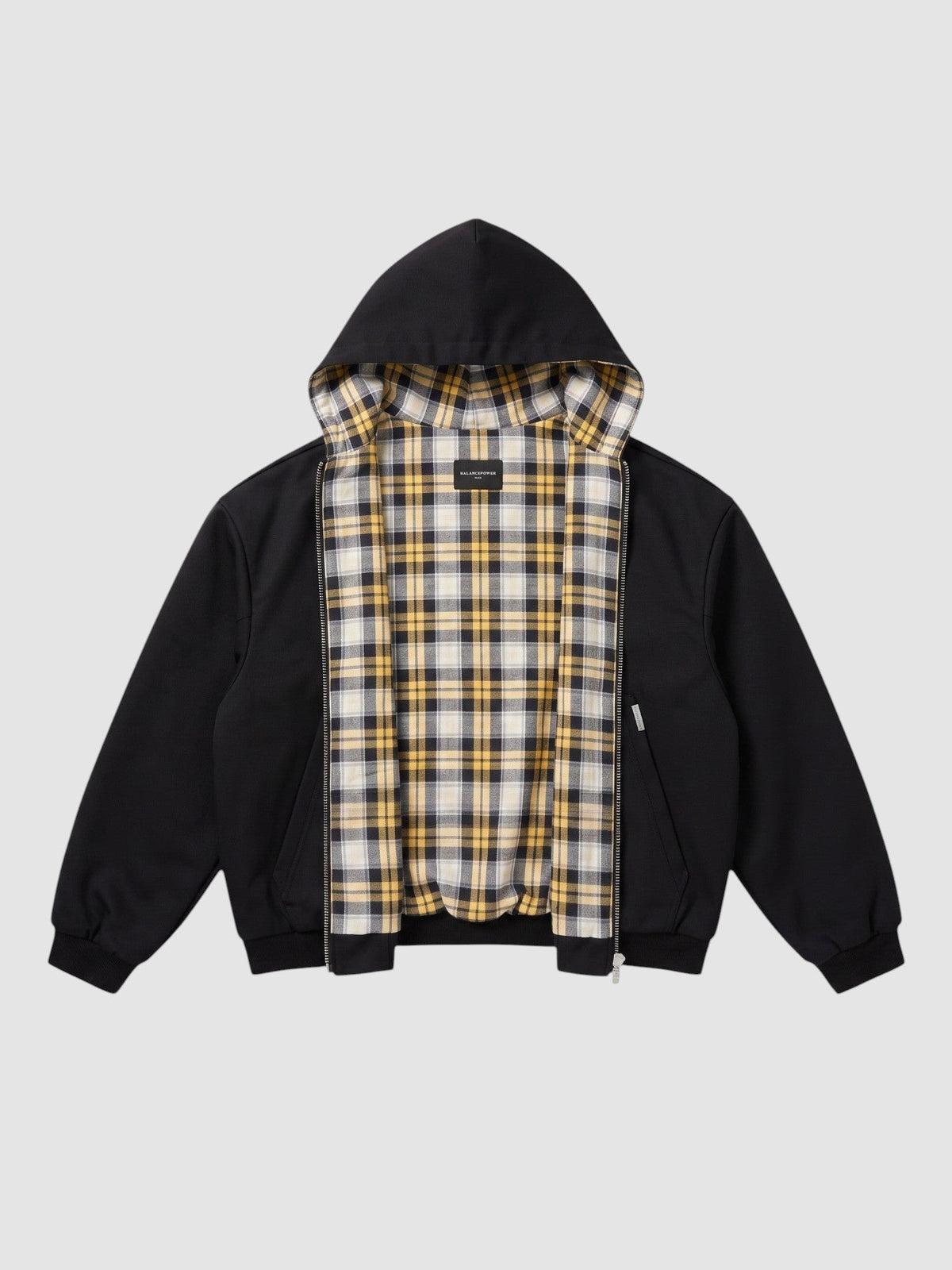 Y2K AVENUE reversible zip-up hoodie featuring a black exterior and a yellow, white, and black plaid tartan lining.