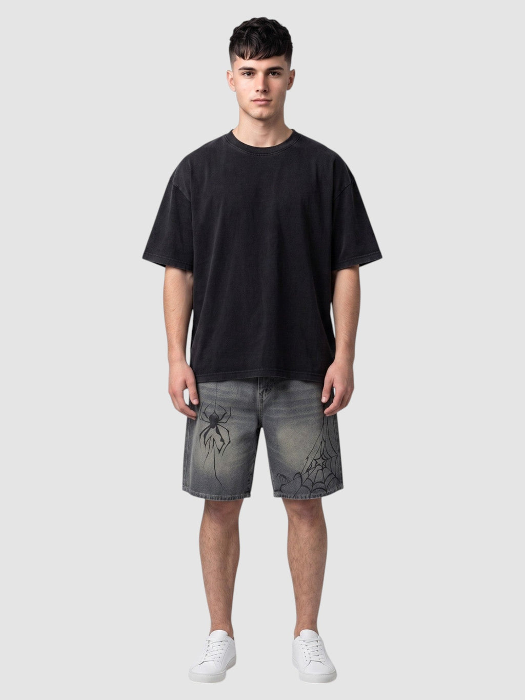 Y2K Avenue model wearing Y2K spider print denim jorts in faded blue with black graphic details and a black t-shirt.