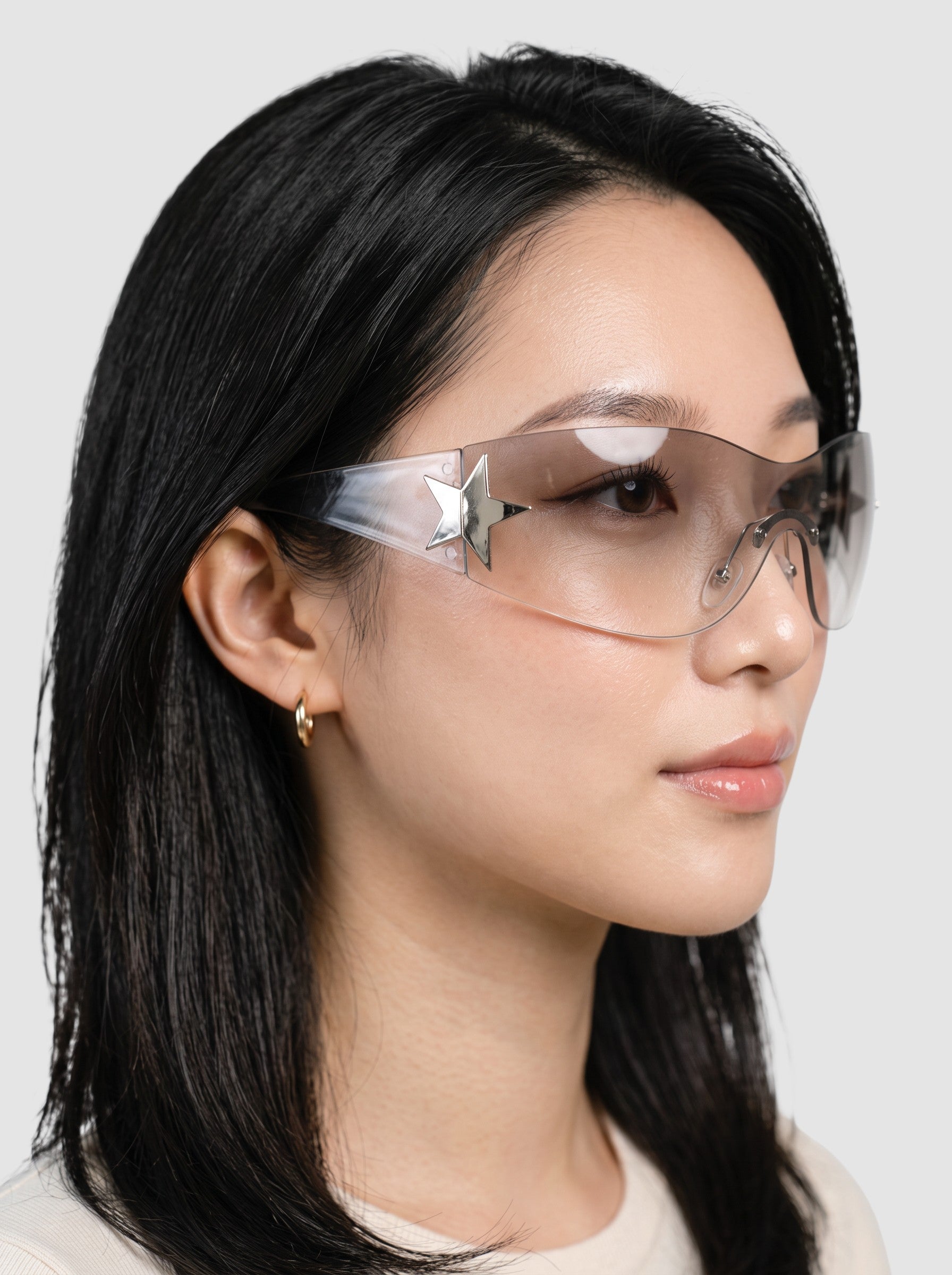 Y2K Avenue Y2K star mask sunglasses with a frameless clear shield lens and silver star detail worn by a model