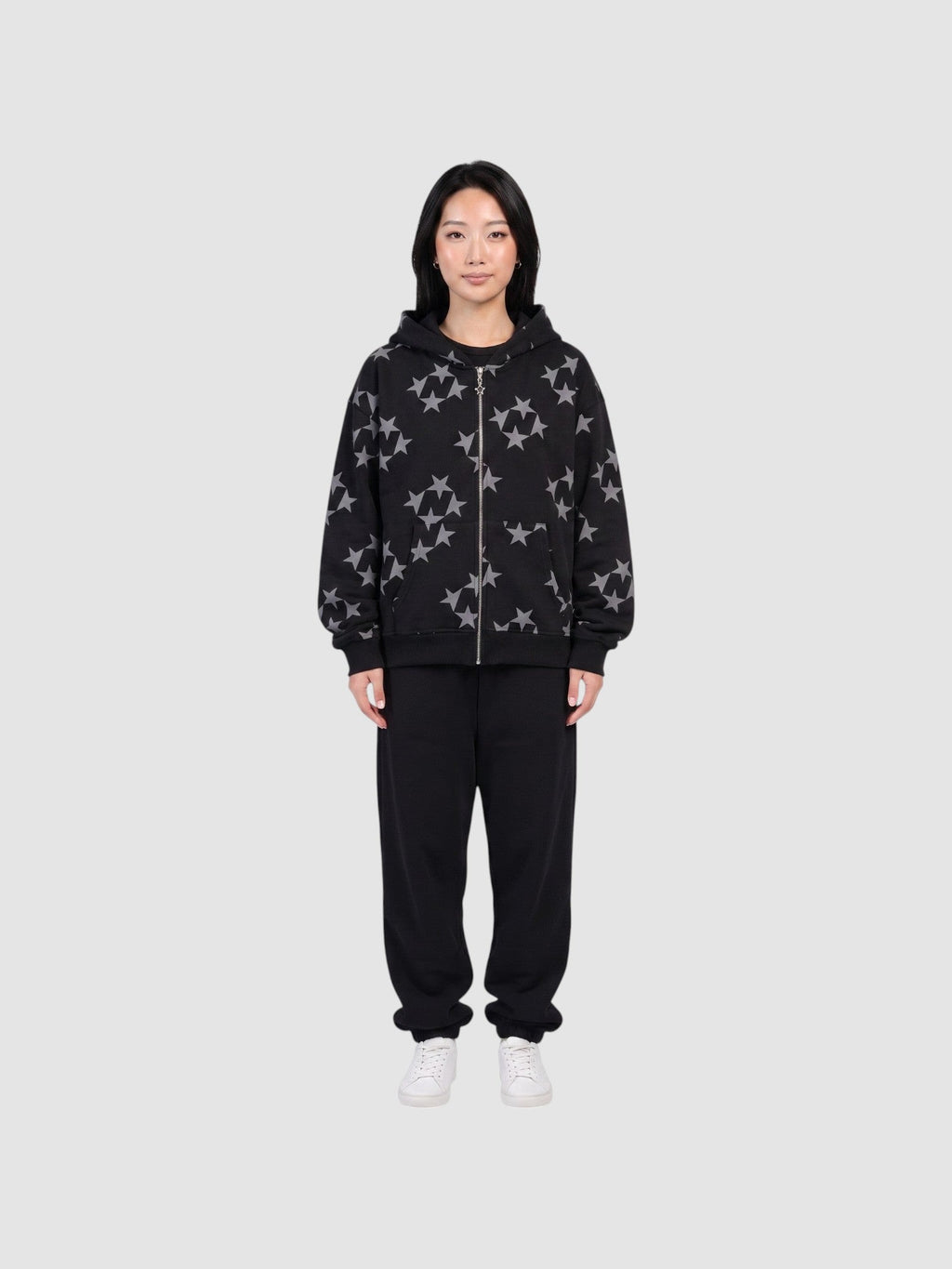 Model wearing a Y2K Avenue black zip-up hoodie with a grey all-over star print, paired with black sweatpants.
