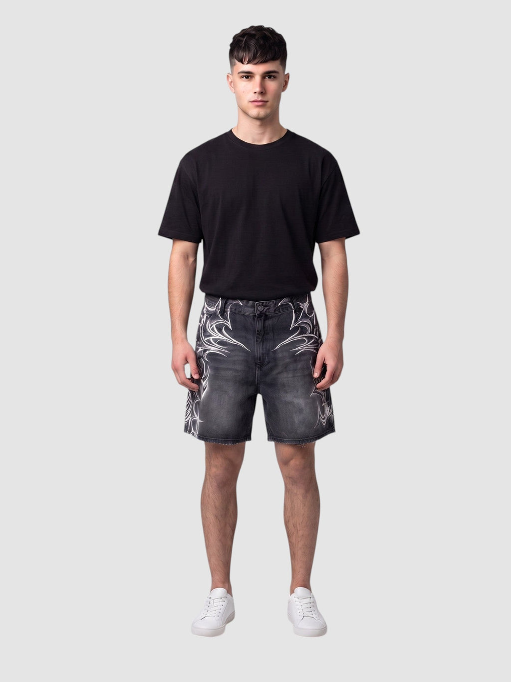 Y2K Avenue black denim jorts featuring white airbrushed tribal motifs, raw hem, and loose fit on a male model.