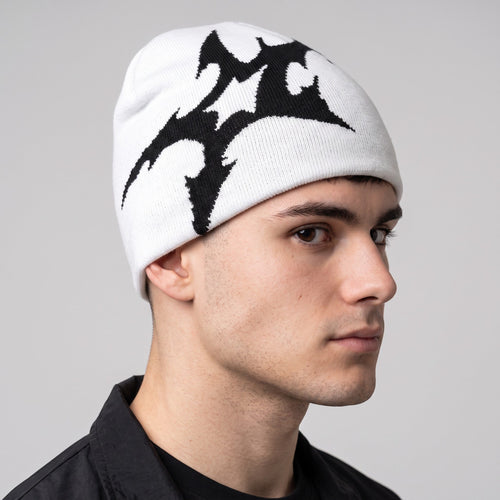 Y2K AVENUE white acrylic knit beanie featuring a bold black tribal-inspired graphic print on a male model