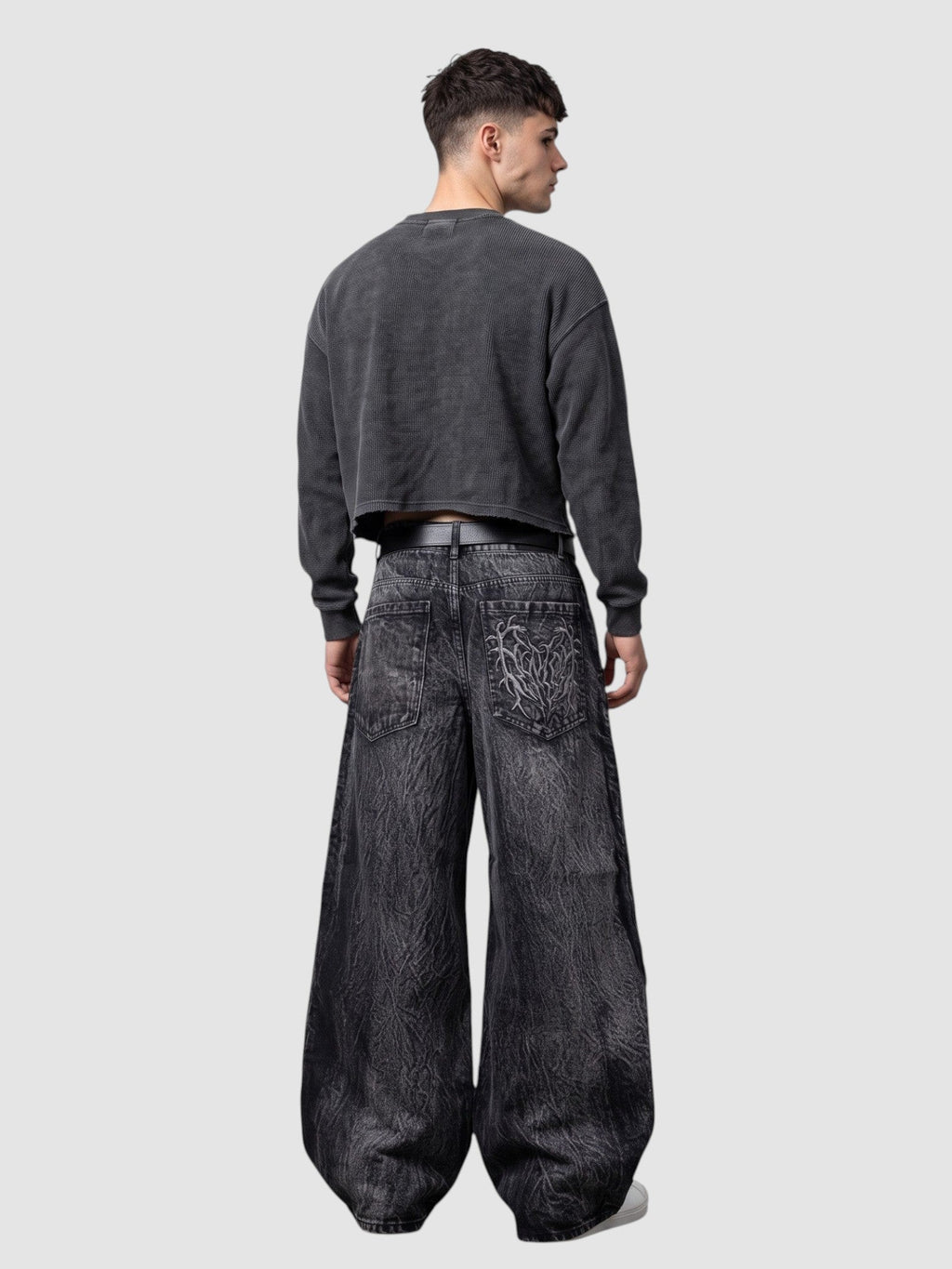 Y2K Avenue wide-leg acid wash black denim jeans with spiderweb embroidery on the back pockets and raw edge details.